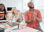 Group of happy diverse businesspeople having a meeting in a modern office at work. Joyful colleagues clapping hands for a coworker while sitting at a table. Creative businesspeople planning together