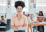 Young cheerful mixed race businesswoman standing with her arms crossed while in an office. Confident hispanic female manager with a curly afro smiling and standing at work