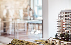 Closeup shot of an architectural model of a building development in an office. Unrecognizable architects discussing blueprints, plans and schematics for their upcoming project blurred in background