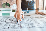 Closeup shot hand of a woman architect holding a pen and looking over plans, blueprints are schematics. One caucasian business woman brainstorming and planning for her upcoming development project