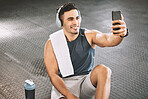Healthy bodybuilder taking selfies in the gym. Fit trainer taking a break from exercise to take a photo on his cellphone. Handsome athlete taking selfies on his smartphone at the gym.