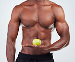 One unrecognizable African American fitness model posing topless with an apple and looking muscular. Confident  male athlete isolated on grey copyspace showing how he keeps a balanced diet