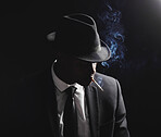 Dapper and confident young man dressed in formal attire and a hat against a dark background. Handsome african american male looking stylish and sophisticated isolated on black. Smoking a cigarette