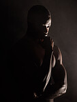 A handsome, muscular young african american man in studio against a dark background. A macho male athlete looking thoughtful isolated on black. Exercising body and mind. A question of mental health