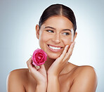 Smiling beautiful woman holding pink rose while posing topless with copyspace. Caucasian model isolated against grey studio background with smooth glowing skin and delicate healthy skincare routine