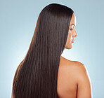 Rear view of a brunette woman with long lush beautiful hair posing against a grey studio background. Mixed race female standing showing her beautiful healthy hair