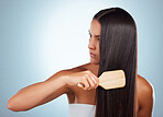 A beautiful young mixed race woman brushing her healthy strong hair against a grey studio background. Hispanic female grooming her hair