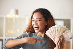 One happy young mixed race woman holding cash, pointing and feeling rich. Excited hispanic woman waving spending money after budgeting finances and saving. Planning for the future or win a lottery