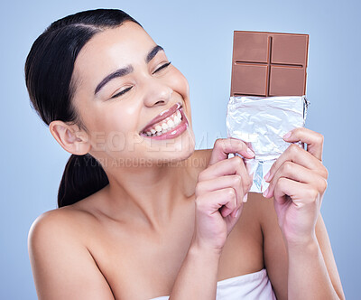 Buy stock photo A beautiful mixed race woman holding a slab of chocolate. Hispanic model snacking on dessert against a blue copyspace background