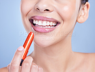 Buy stock photo Closeup of a beautiful young mixed race woman with glowing skin posing against blue copyspace background. Hispanic woman applying lipstick in a studio