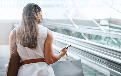 Buy stock photo Rear view of a Trendy unrecognizable woman using a cellphone while out on a shopping spree. Female enjoying retail therapy while staying connected with her smartphone. Calling to find a sale and discount. Planning to spend money.