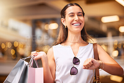 Buy stock photo Portrait of a Young mixed race woman during a shopping spree in a mall. One hispanic female only enjoying retail therapy. Shopaholic holding bags smiling and looking happy while walking in a shopping mall