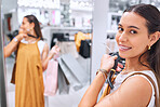 Portrait of a trendy young woman enjoying her weekend by spending money on a shopping spree. Smiling female fitting on clothes in a store. Mixed race shopper happy about finding a sale and discount