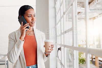 Buy stock photo Young mixed race businesswoman on a call using her phone while drinking a coffee alone in an office at work. Confident hispanic businessperson looking out of a window drinking a coffee and talking on the phone while standing at work