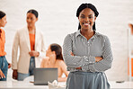 Young happy african american businesswoman standing with her arms crossed in an office at work. Confident cheerful black female businessperson standing in a meeting at work