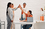 Four happy businesswomen joining their hand together in an office at work. Diverse group of cheerful businesspeople giving each other a high five for support