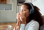 Woman listening to music at home. Young woman smelling fresh,cleaned laundry. Mixed race woman enjoying the scent of clean clothing. Hispanic woman enjoying fresh, fragrant washed laundry.