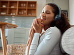 Woman enjoying the feel of a soft top. Young woman listening to music, cleaning laundry. Mixed race woman holding fresh, washed clothing. Happy woman rubbing clean clothing on her face