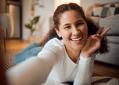 Buy stock photo Cheerful woman taking a selfie at home. Young woman making the peace sign with her finger. Young girl relaxing taking a selfie. Comfortable woman resting and relaxing at home