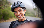 Portrait of a happy smiling mixed race athletic young woman taking a selfie during a break from cycling outside .Sporty fit mixed race female wearing a helmet and taking a photo of herself