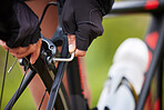 Closeup of an unrecognizable female cyclist fixing her bicycle using an allen key outside. Uknown woman fixing her bike while out cycling in nature