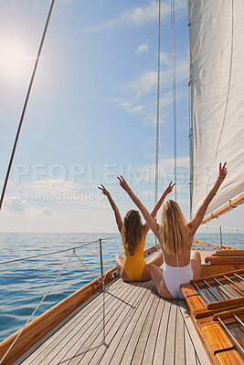 Buy stock photo Two friends in swimsuits making peace signs celebrating on a boat cruise. Two women cheerfully celebrating making peace signs sitting on a boat. Happy friends celebrating together on a cruise