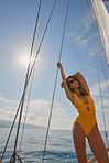 Young woman in yellow swimsuit standing on boat deck posing holding rigging cable. Young woman on holiday cruise posing on a boat. Beautiful woman in yellow swimwear holding boat rigging cable.