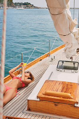 Buy stock photo Young woman in a red bikini sunbathing on a boat lying down using her smartphone to send messages. Woman lying on boat using smartphone to scroll apps while sunbathing.