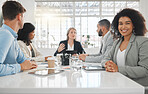 Portrait of a young happy mixed race businesswoman with a curly afro sitting in a meeting at work. Group of businesspeople having a meeting together at a table. Business professionals talking and planning in an office