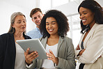 Group of happy diverse businesspeople standing and using a digital tablet together in an office. Content business professionals working and planning on a digital tablet at work
