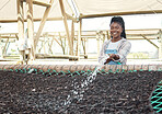 Happy farmer watering a bed of soil. Young farmer watering a bed of dirt. Farmer watering plants with a hose. Smiling farm worker watering soil. Farmer working to conserve dirt