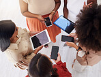 Above view of diverse group of unknown ambitious businesswomen huddled together and using technology in middle. Ethnic team of professional colleagues standing to bluetooth and sync schedule in office