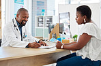African american doctor in a consult with a patient. Young woman talking to her doctor during a checkup. Doctor talking to a patient about its medical report on a clipboard.