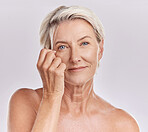 Portrait of a happy smiling mature caucasian woman looking positive and cheerful while caring for her skin in a studio against purple copyspace background. Older woman doing her skincare routine