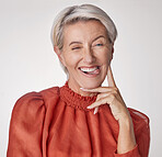 Portrait of one quirky, playful, mature caucasian woman isolated against a grey studio background and making facial expressions. Senior touching her face and feeling silly, biting her tongue, winking