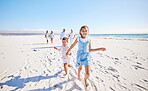 Portrait of adorable little girl and boy holding hands while running together on sandy beach while family follow in the background. Carefree sibling brother and sister having fun during summer beach vacation with their parents and grandparents family