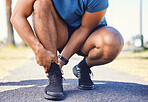 Closeup of active mixed race man holding his ankle in pain while out for a run. Unknown athlete suffering from discomfort from a sprained  ankle or sports injury