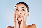 Closeup face beautiful young mixed race woman. Attractive female touching her face in studio isolated against a blue background. A skincare regime to keep your skin soft, smooth, glowing and healthy