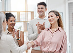 Happy businesswomen shaking hands while their colleagues clap hands in support in a meeting at work. Business professionals greeting and making deals with each other. Boss hiring an employee