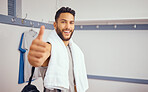 Mixed race player giving the thumbs up in his gym. Portrait of a handsome squash player in his gym locker room. Professional hispanic player showing a symbol of support with his hands in the gym