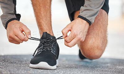 Buy stock photo Closeup shot of a young male athlete tying his shoelaces before going on a run outside. Sporty man fastening his running footwear is fastened before a jog outside. Increase your endurance with cardio 