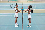 Cheerful women holding hands over the net on a tennis court. Young women support each other after tennis practice. Friends celebrate each other after a game of tennis. Friends on the tennis court