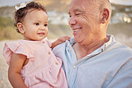 Mature mixed race man and his granddaughter at the beach. Cute little girl spending time with her grandfather outside at sunset. Happy grandparent bonding with his grandchild outdoors during summer