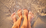 Two sets of feet of a parent and young child in the water on the beach from above. A parent and little kid wetting their feet together, bonding in the ocean on holiday. Two peoples feet in the waves 