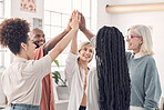 Group of joyful diverse businesspeople giving each other a high five in an office at work. Business professionals having fun joining their hands in support and unity during a meeting