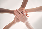 Group of diverse businesspeople piling their hands together in an office at work. Business professionals having fun standing with their hands stacked for support and unity from below