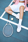 Close up of trendy young tennis player wearing a pink jacket while sitting on a tennis court. Young hispanic sportswoman sitting with a tennis racket and ball, from above