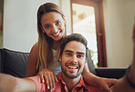 Close up portrait of loving young caucasian couple sitting and taking selfie as they spend time together. Young man holding mobile phone taking photo with girlfriend smiling and looking happy to be together