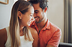 Close up of funny young caucasian couple touching heads laughing and looking happy to be together while spending time at home. Loving smiling boyfriend embracing girlfriend from behind