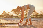 Full length yoga woman getting mat ready for outdoor practice in remote nature. Beautiful caucasian person rolling mat after stretching alone at sunset. Young, active, zen, serene with healthy routine